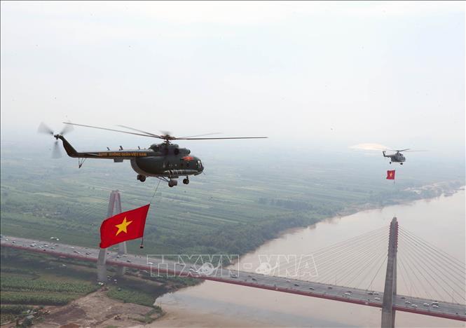 Biên đội máy bay trực thăng của Quân chủng Phòng không - Không quân treo cờ Đảng và cờ Tổ quốc bay vào khu vực trung tâm Thủ đô Hà Nội. Ảnh: Trọng Đức - TTXVN