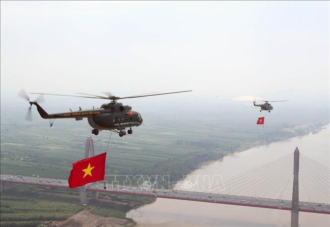 Biên đội máy bay trực thăng của Quân chủng Phòng không - Không quân treo cờ Đảng và cờ Tổ quốc bay vào khu vực trung tâm Thủ đô Hà Nội. Ảnh: Trọng Đức - TTXVN