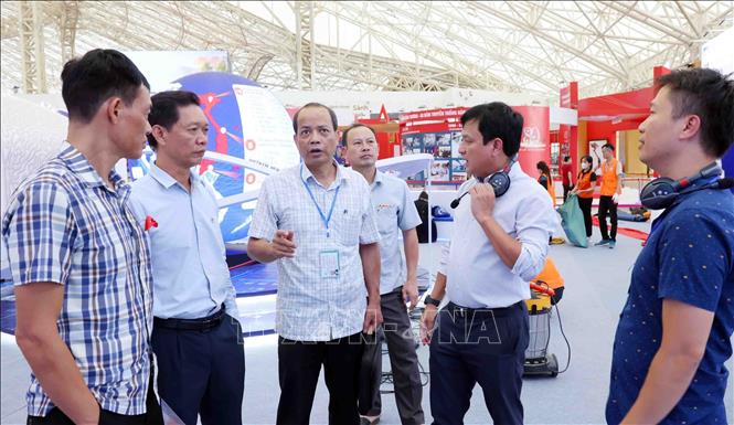 Lãnh đạo các đơn vị thông tin của TTXVN trao đổi công tác chuẩn bị tại khu trưng bày. Ảnh: Phạm Kiên - TTXVN