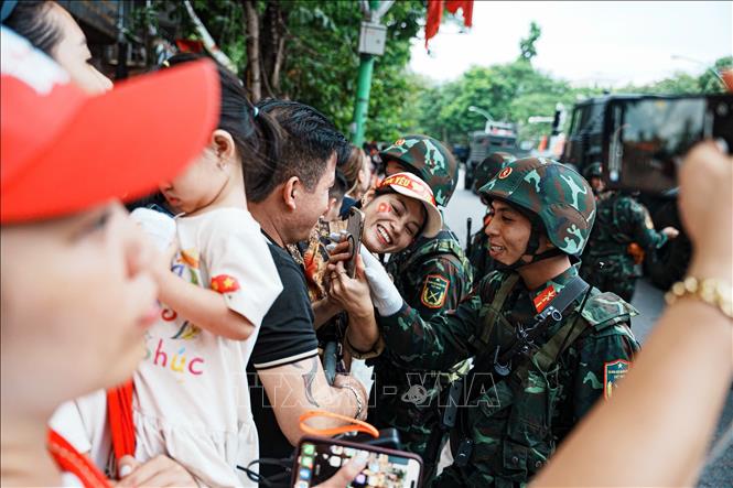 Các chiến sĩ giao lưu với người dân hai bên đường. Ảnh: Phạm Tuấn Anh - TTXVN