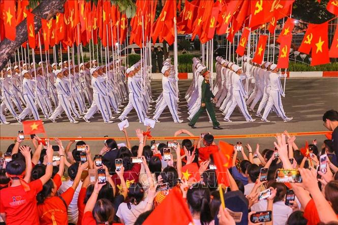 Người dân cổ vũ khi Khối cờ Đảng, cờ Tổ quốc đi qua phố Văn Cao. Ảnh: Hoàng Hiếu - TTXVN