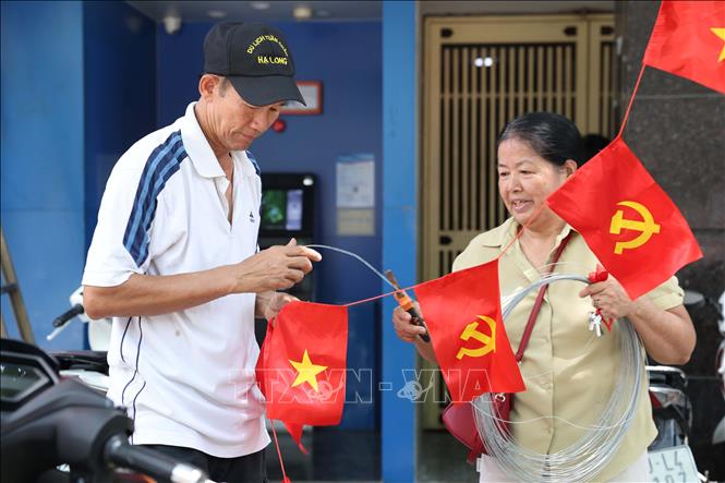 Người dân cẩn thận treo những dải cờ nhỏ trên phố, góp phần làm rực rỡ thêm không gian đô thị. Ảnh: Vũ Quang – TTXVN