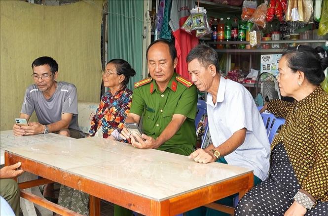 Công an phường Vị Tân hướng dẫn ông Trần Tấn Tài (áo trắng) cùng bà con hàng xóm thực hiện dịch vụ công trực tuyến. Ảnh: TTXVN phát