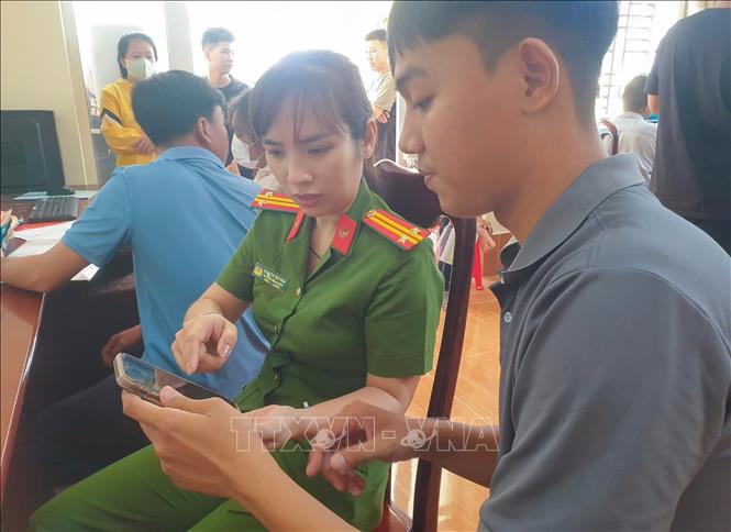 Trung tá Phạm Thị Thùy Nga, Phó trưởng Công an phường Vị Thanh, thành phố Cần Thơ hướng dẫn người dân thực hiện thủ tục hành chính trên ứng dụng VNeID. Ảnh: TTXVN phát