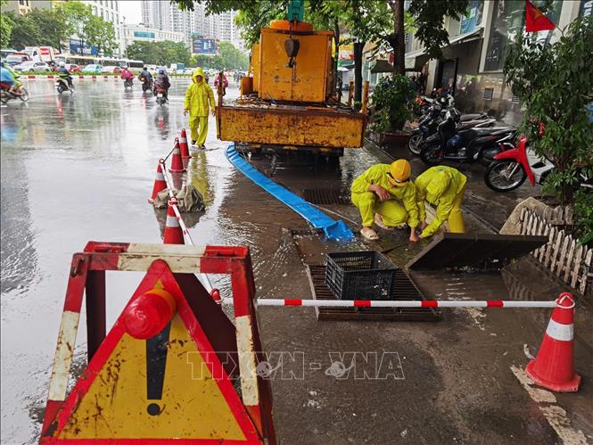 Công nhân ứng trực, xử lý thoát nước trên phố Minh Khai. Ảnh: Thanh Tùng - TTXVN