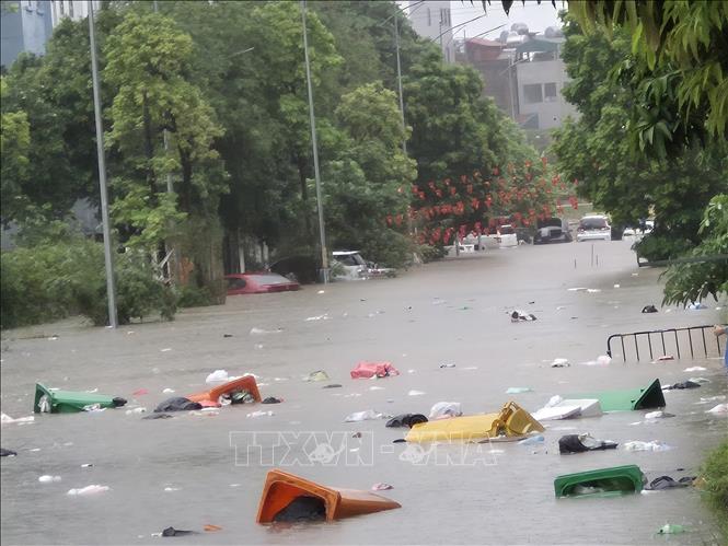 Trong mưa ngập kéo theo rác, tiềm ẩn ô nhiễm môi trường. Ảnh: Nguyễn Thắng - TTXVN