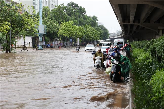 Đường Nguyễn Xiển “biến” thành sông do ngập úng cục bộ, người dân di chuyển khó khăn. Ảnh: Vũ Quang - TTXVN
