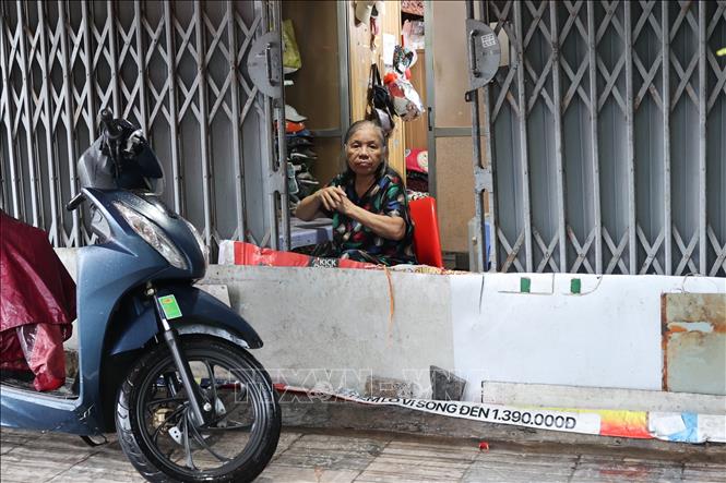Người dân trên đường Giải Phóng dùng nhiều dụng cụ để ngăn nước tràn vào nhà. Ảnh: Vũ Quang - TTXVN