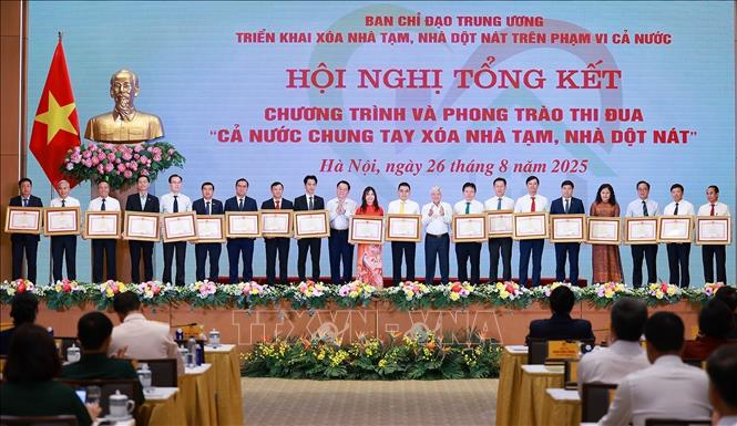 Trưởng Ban Tuyên giáo và Dân vận Trung ương Nguyễn Trọng Nghĩa và Chủ tịch Uỷ ban Trung ương MTTQ Việt Nam Đỗ Văn Chiến trao Bằng khen của Thủ tướng Chính phủ cho các tập thể có thành tích xuất sắc trong Phong trào thi đua “Cả nước chung tay xóa nhà tạm, nhà dột nát”. Ảnh: Dương Giang-TTXVN 
