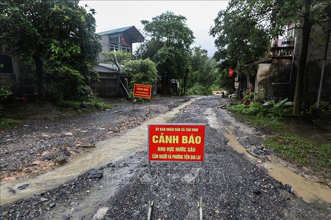 Biển cảnh báo được đặt tại điểm ngập lụt trên con đường liên xã từ xóm Nước Vải đi Xóm Rụt, xã Tân Vinh. Ảnh: Trọng Đạt - TTXVN