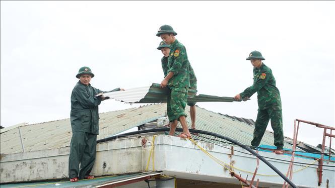 Lực lượng bộ đội biên phòng hỗ trợ người dân xã Thiên Cầm thu dọn mái tôn bị bão cuốn bay. Ảnh: Hữu Quyết - TTXVN