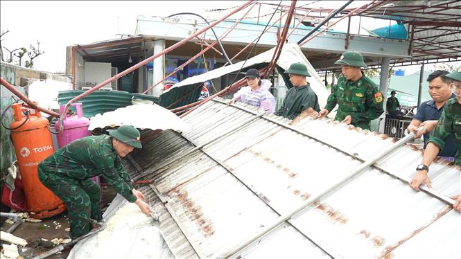 Lực lượng bộ đội biên phòng hỗ trợ người dân xã Thiên Cầm thu dọn mái tôn bị bão cuốn bay. Ảnh: Hữu Quyết - TTXVN