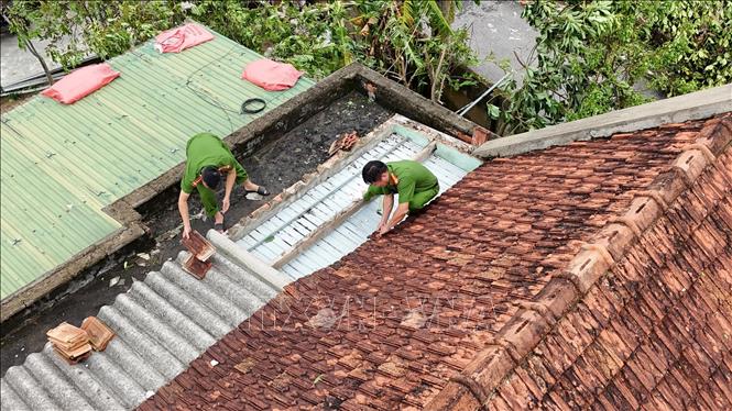 Lực lượng công an tham gia hỗ trợ giúp người dân xã Lộc Hà lợp lại mái nhà bị tốc do bão. Ảnh: Hữu Quyết - TTXVN