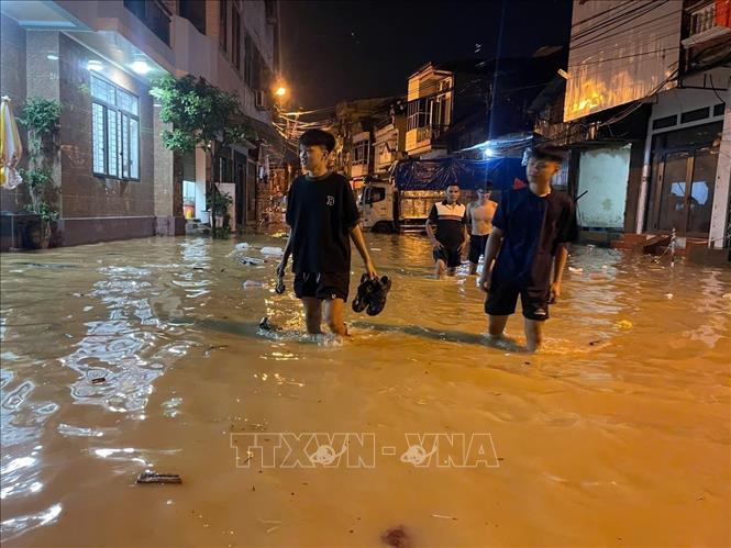 Người dân chủ động di dời khi nước sông dâng vào đường Thanh Niên. Ảnh: Đinh Thùy - TTXVN