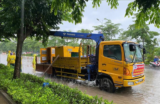 Lực lượng chức năng khẩn trương tiêu thoát nước trên đường Đàm Quang Trung. Ảnh: Nguyễn Thắng - TTXVN