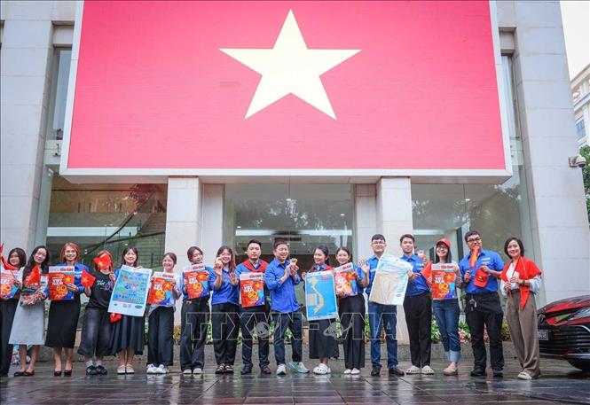 Đoàn niên thanh niên check in tại Trụ sở Thông tấn xã Việt Nam với lá cờ tổ quốc kích thước lớn. Ảnh: Hoàng Hiếu - TTXVN