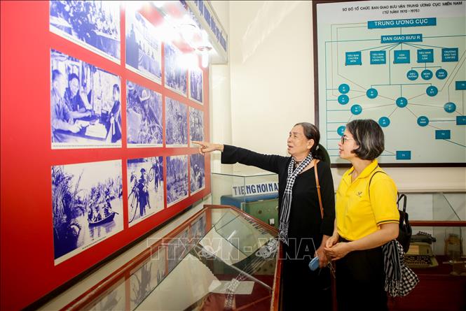 Bà Phạm Thị Huê, 77 tuổi, cựu chiến sĩ giao liên (người chỉ tay) xúc động khi xem lại những hình ảnh về người giao liên. Ảnh: Giang Phương - TTXVN