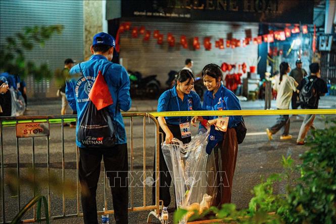 Tình nguyện viên thu gom rác sau buổi Sơ duyệt sự kiện A80. Ảnh: Phạm Tuấn Anh-TTXVN