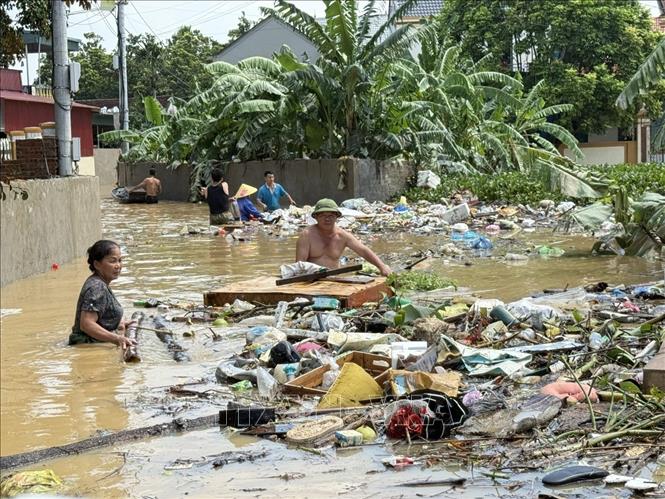 Người dân tập trung thu gom rác thải để sớm đưa cuộc sống trở lại ổn định. Ảnh: Hoa Mai - TTXVN