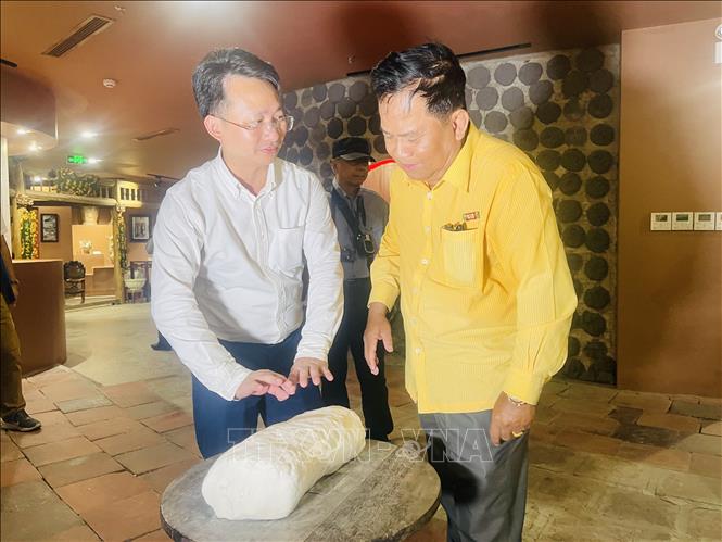 Phó Giám đốc Sở Du lịch Hà Nội Trần Trung Hiếu giới thiệu với phóng viên về nguyên liệu gốm Bát Tràng. Ảnh: Tuyết Mai - TTXVN 