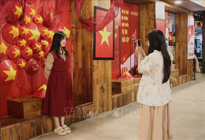 Thanh niên check - in tại điểm trang hoàng cờ đỏ sao vàng. Ảnh: Nguyễn Hằng - TTXVN