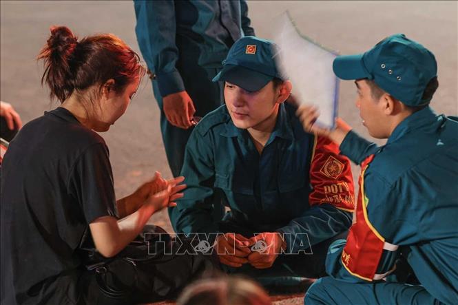 Lực lượng dân quân tự vệ hỗ trợ một người dân gặp vấn đề về sức khỏe tại khu vực cầu vượt Nguyễn Chí Thanh, đêm 29/8. Ảnh: Hoàng Hiếu - TTXVN