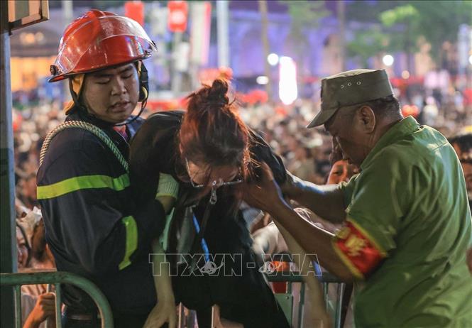 Lực lượng chức năng hỗ trợ người dân bị ngạt thở, đuối sức do chờ đợi lâu trong đám đông và thời tiết không thuận lợi, đêm 29/8. Ảnh: Hoàng Hiếu - TTXVN