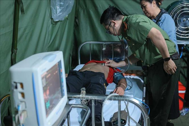 Thiếu tá, bác sĩ Nguyễn Xuân Khánh kiểm tra sức khoẻ cho người dân bị ngã, có hiện tượng co giật khi đi xem lễ diễu binh, diễu hành tại trạm y tế dã chiến phố Liễu Giai. Ảnh: Hoàng Hiếu - TTXVN