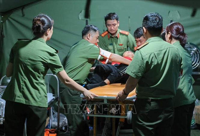 Các bác sĩ của công an Hà Nội khẩn trương sơ cứu cho người dân bị ngã, có hiện tượng co giật khi đi xem lễ diễu binh, diễu hành tại trạm y tế dã chiến phố Liễu Giai. Ảnh: Hoàng Hiếu - TTXVN