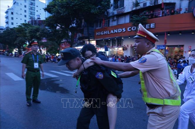 Lực lượng chức năng hỗ trợ chăm sóc sức khỏe một người dân bị ngất trên phố Lê Duẩn (ảnh chụp lúc 5g45 ngày 30/8). Ảnh: Trần Việt - TTXVN