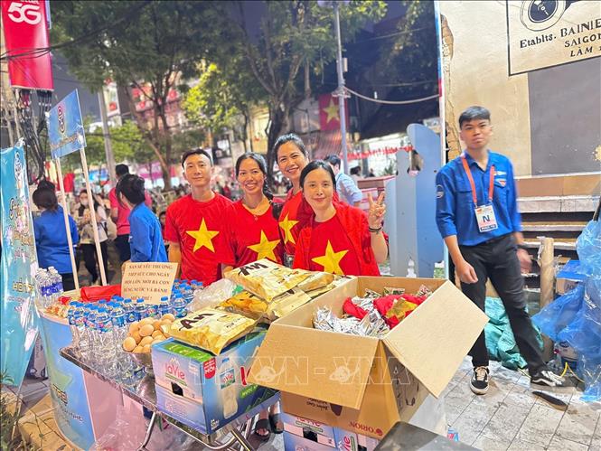 Vợ chồng chị Nguyễn Hoa và anh Tú cùng bạn bè chuẩn bị đồ ăn và nước uống phát miễn phí cho người dân xem Lễ tổng duyệt diễu binh, diễu hành A80 diễn ra vào sáng 30/8 tại khu vực ngã 5 Cửa Nam. Ảnh: Công Đạt - TTXVN
