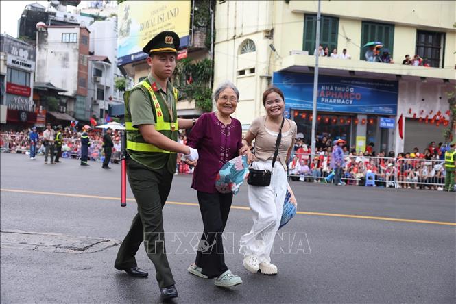 Lực lượng an ninh giúp đỡ người có công và cựu chiến binh vào khu vực ghế ngồi ưu tiên. Ảnh: Công Đạt - TTXVN