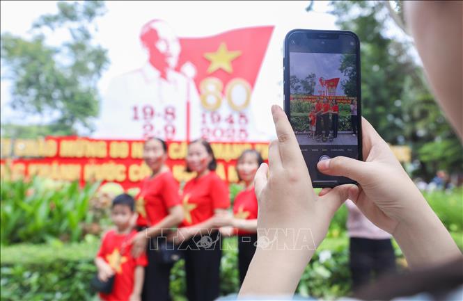 Check-in trong sắc cờ đỏ sao vàng, người dân lưu lại khoảnh khắc ý nghĩa tại khu vực pano có hình ảnh Bác Hồ. Ảnh: Thành Phương-TTXVN