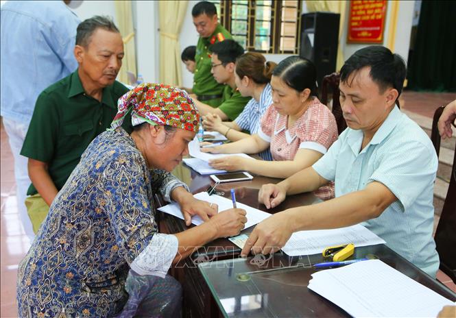 Người dân phường Trường Thi, tỉnh Ninh Bình ký giấy xác nhận số nhân khẩu trong gia đình để nhận quà Tết độc lập. Ảnh: Công Luật - TTXVN 