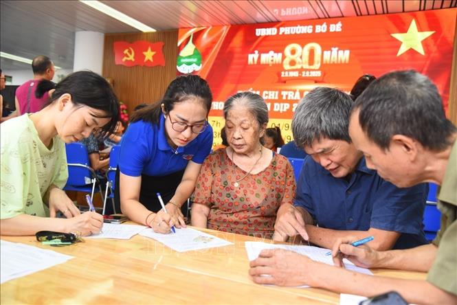 Đoàn viên phường Bồ Đề hỗ trợ hướng dẫn người dân đăng ký nhận quà dịp 2/9. Ảnh: Minh Quyết - TTXVN