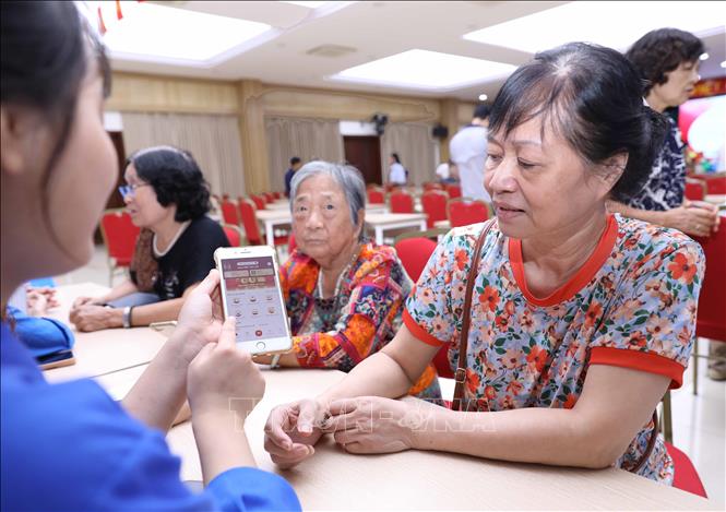 Sinh viên tình nguyện hỗ trợ người dân làm thủ tục nhận quà Tết Độc lập trên ứng dụng VNeID. Ảnh: Thành Phương – TTXVN