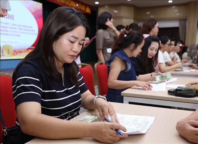 Cán bộ phường Cửa Nam thực hiện thủ tục tra cứu để tiến hành chi trả quà Tết Độc lập cho người dân. Ảnh: Thành Phương - TTXVN