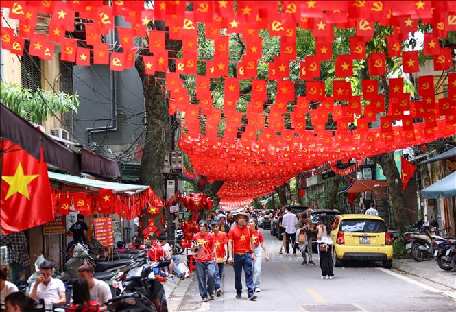 Người dân đi dưới bóng cờ hoa ngập tràn sắc đỏ, mang theo tinh thần tự hào Việt Nam khắp các nẻo đường Hà Nội. Ảnh: Thanh Tùng - TTXVN