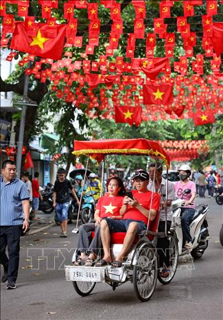 Người dân đi dưới bóng cờ hoa ngập tràn sắc đỏ, mang theo tinh thần tự hào Việt Nam khắp các nẻo đường Hà Nội. Ảnh: Thanh Tùng - TTXVN
