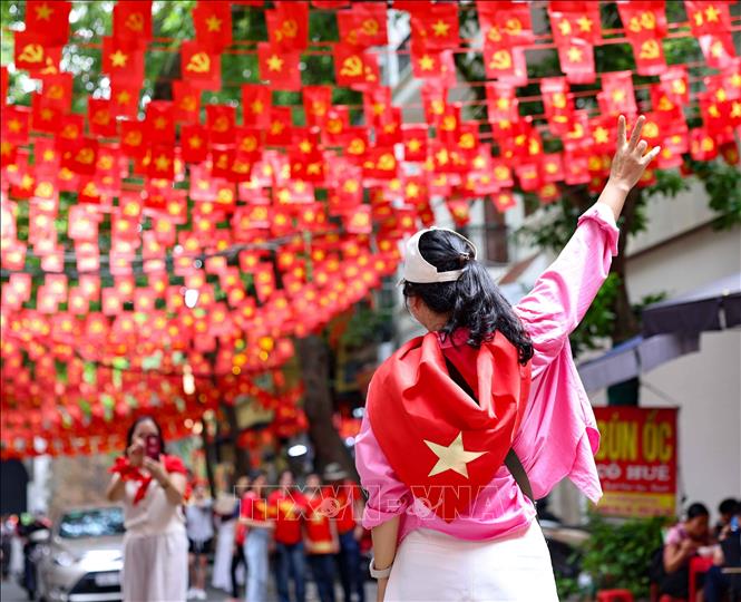 Người dân chụp ảnh dưới bóng cờ bay rực rỡ trên phố Đặng Dung. Ảnh: Thanh Tùng - TTXVN