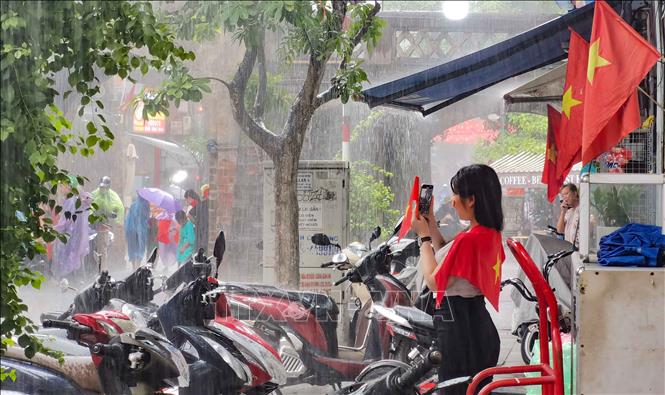 Xuất hiện mưa rào xong nhanh tạnh nên không ảnh hưởng nhiều tới việc đi lại, của người dân, thăm quan phố cổ của du khách. Ảnh: Thanh Tùng - TTXVN