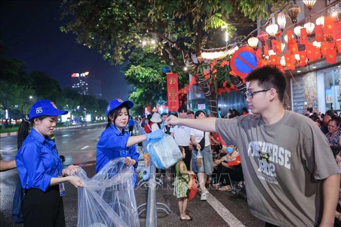 Lực lượng thanh niên tình nguyện hỗ trợ người dân dọn dẹp vệ sinh môi trường trên các tuyến phố. Ảnh: Hoàng Hiếu - TTXVN