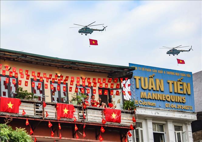 A formation of helicopters of the Air Defense – Air Force carrying the national flag and party flag flies into downtown Hanoi. 