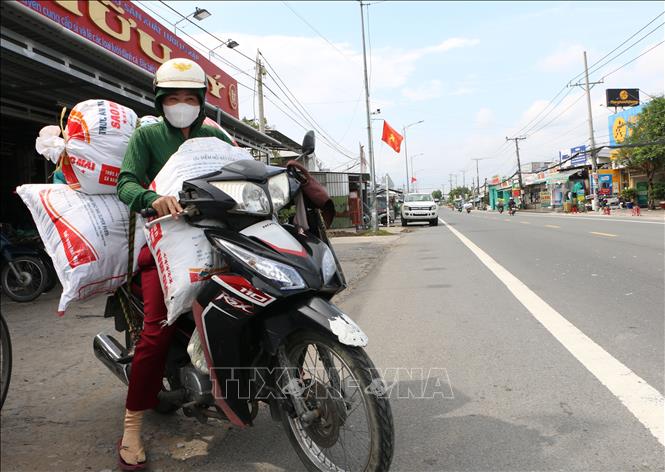 Nhân công nhận vật liệu tại cơ sở vận chuyển về nhà để gia công sản phẩm. Ảnh: Tuấn Phi-TTXVN