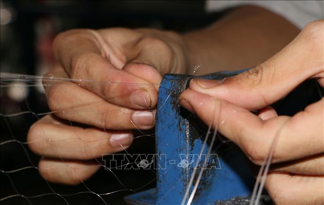 Sử dụng máy để bấm chì cho lưới. Ảnh: Tuấn Phi-TTXVN