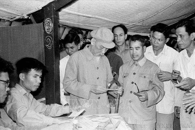 Phóng viên VNTTX Đinh Chương (người đứng phía sau Bác Hồ) tháp tùng đưa tin Chủ tịch Hồ Chí Minh bỏ phiếu bầu cử HĐND các cấp (27/4/1969). Ảnh: TTXVN