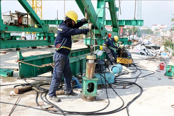 Các kỹ sư, công nhân thuộc Tổng công ty Xây dựng Trường Sơn (Binh đoàn 12) thực hiện tháo hạ gầm đáy của cầu. Ảnh: Tạ Toàn – TTXVN