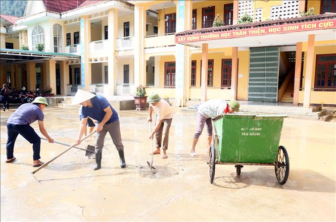Các thầy giáo Trường Tiểu học và THCS Thượng Hóa (xã Kim Phú, Quảng Trị) vệ sinh bùn đất ở sân trường, chuẩn bị cho lễ khai giảng. Ảnh: Tá Chuyên – TTXVN