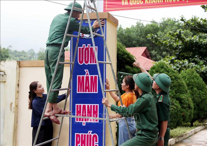 Cán bộ chiến sỹ Đồn Biên phòng Cà Xèng và giáo viên Trường mầm non Thượng Hóa (xã Kim Phú, Quảng Trị) treo băng rôn, khẩu hiệu tại công trường, chuẩn bị cho lễ khai giảng năm học mới. Ảnh: Tá Chuyên – TTXVN