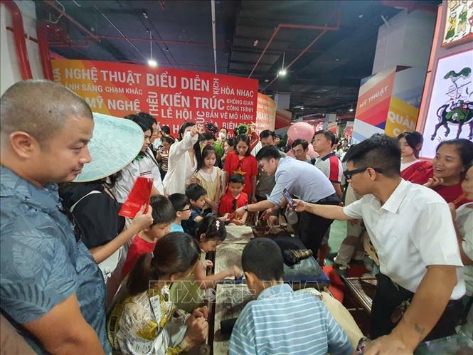Người dân tới xem và trải nghiệm ở gian trưng bày tranh dân gian Đông Hồ-Mộc bản (Bắc Ninh) tại Trung tâm Hội chợ Triển lãm quốc gia (Đông Anh, Hà Nội), ngày 7/9. Ảnh: Nguyễn Trọng Lịch- TTXVN

